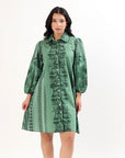 Woman wearing a green hand printed patterned dress on a white background
