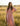 Woman in a pink dress standing in a field with a straw hat